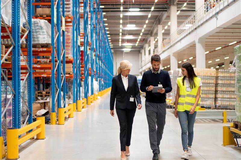three people walking in a warehouse